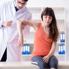 Medico esegue un esame neurologico su una paziente, testando i riflessi del braccio con un martelletto.