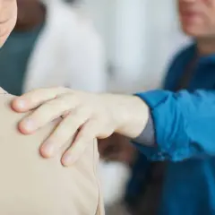 Mano appoggiata sulla spalla, un gesto di supporto. Forse un collega che fa un "jerk test" per verificare la stabilità, o un amico che offre conforto.
