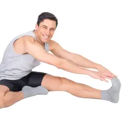 Uomo sorridente fa stretching, allungando la gamba destra. Attenzione a non forzare per evitare una lesione bicipite femorale.