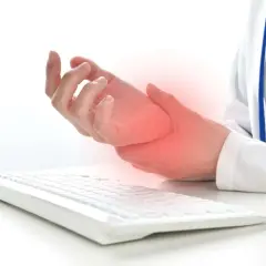 Mano che tiene il polso, con un'area rossa che indica dolore, vicino a una tastiera. Possibili tendiniti diffuse dovute all'uso prolungato del computer.