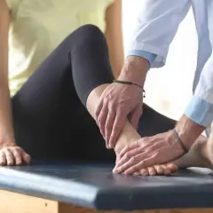 Medico esegue uno squeeze test alla caviglia di una paziente per valutare un possibile infortunio.