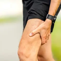 Atleta con mano sulla coscia, indicando una possibile lesione muscolare.