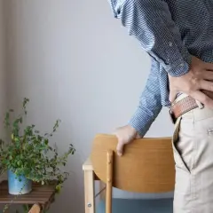 Uomo con mano sulla schiena, soffre di un colpo della strega. Tempi di recupero lunghi e dolorosi.