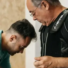 Uomo con giubbotto EMS, assistito da un trainer, per contrastare l'atrofia muscolare.