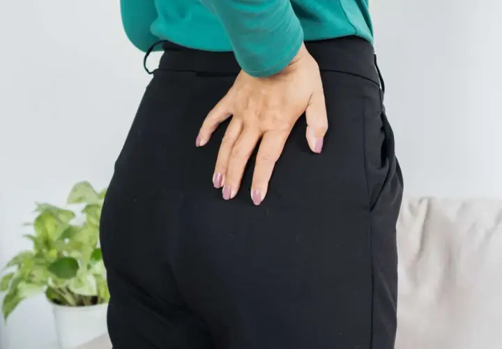 Donna si tocca il fianco, indicando dolore da tendinopatia degenerativa.
