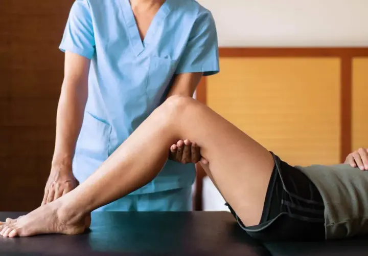 Fisioterapista esamina il ginocchio di un paziente, un passo importante per capire il significato di entesite e il suo trattamento.