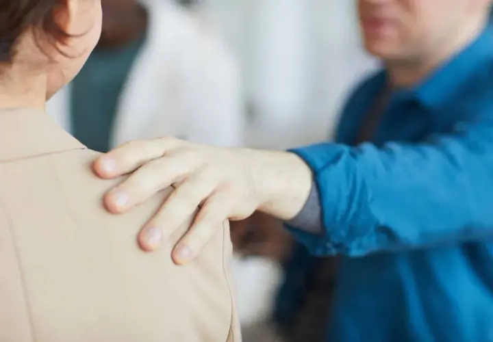 Mano appoggiata sulla spalla, un gesto di supporto. Forse un collega che fa un "jerk test" per verificare la stabilità, o un amico che offre conforto.