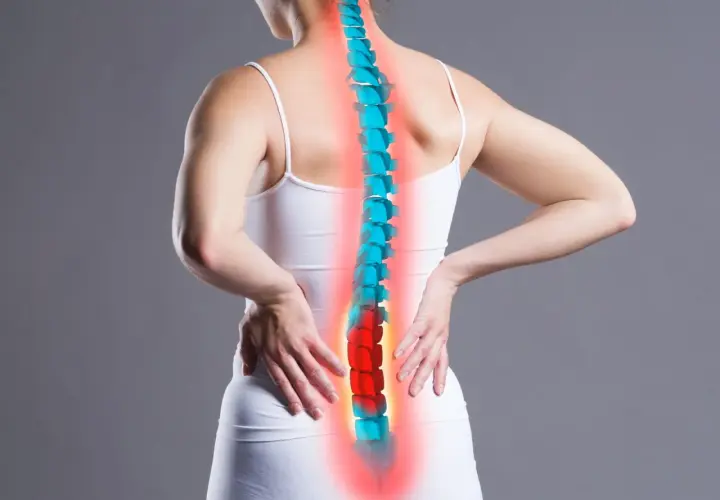 Donna con mani sulla schiena, colonna vertebrale evidenziata in rosso e blu. Il dolore lombare, il rachialgia significato, è rappresentato dal colore rosso.