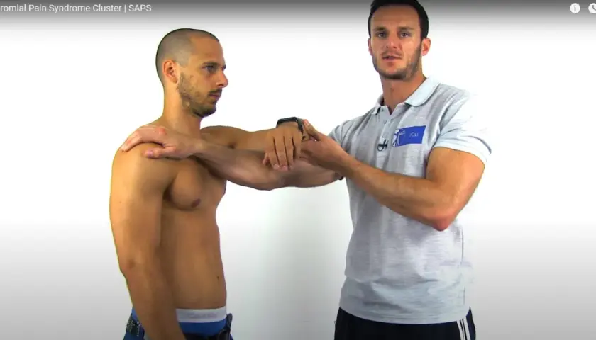 Un fisioterapista esegue un impingement test su un paziente, valutando la spalla.