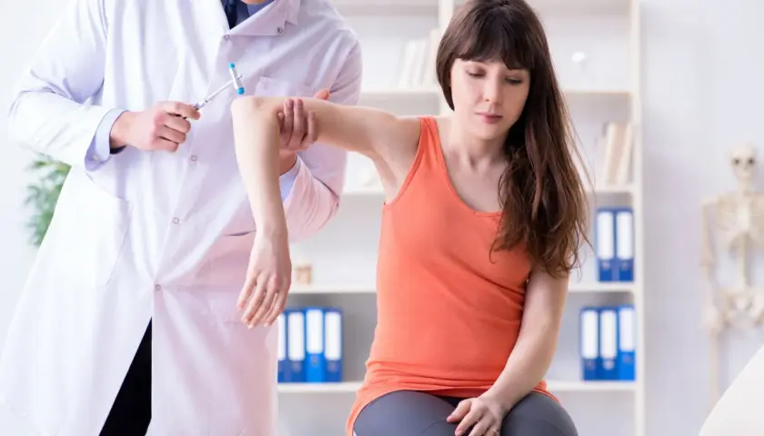 Medico esegue un esame neurologico su una paziente, testando i riflessi del braccio con un martelletto.