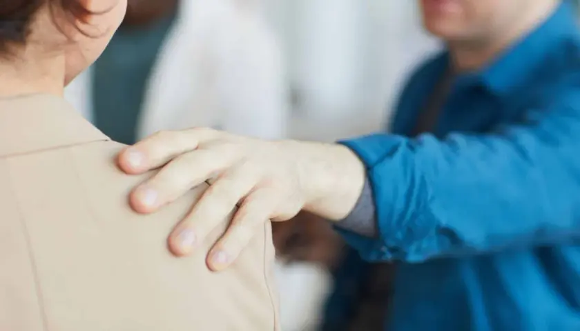 Mano appoggiata sulla spalla, un gesto di supporto. Forse un collega che fa un "jerk test" per verificare la stabilità, o un amico che offre conforto.