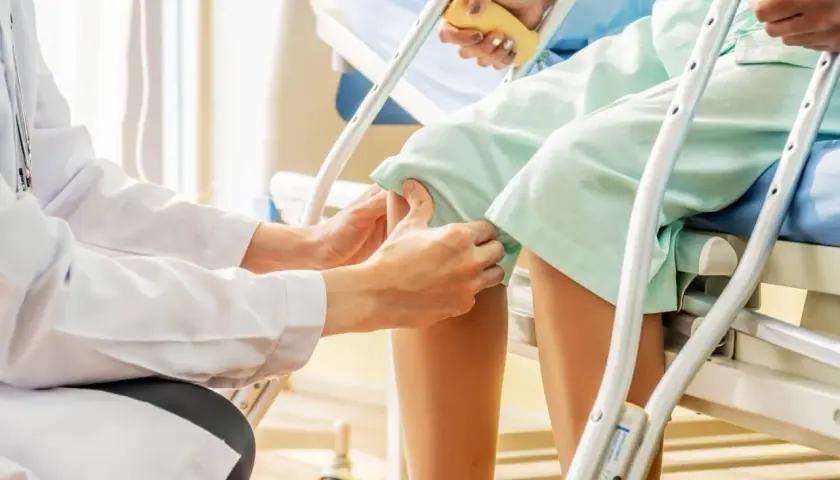 Medico esegue il Lachman test su un paziente in ospedale, valutando la stabilità del ginocchio.