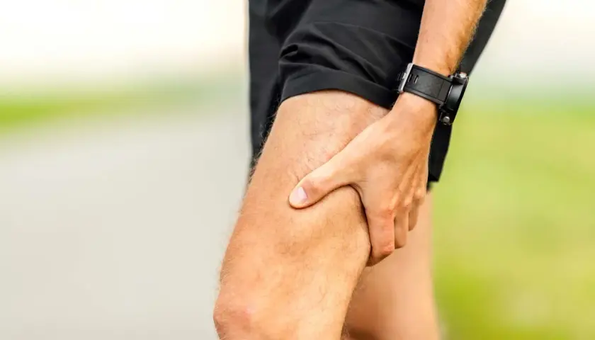 Atleta con mano sulla coscia, indicando una possibile lesione muscolare.