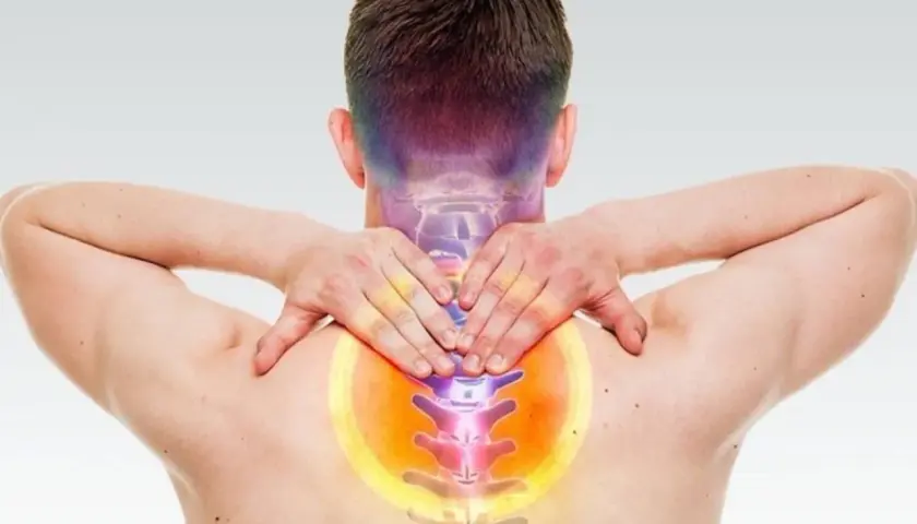 Uomo con mani sul collo e schiena, evidenziando dolore e possibili conseguenze di frattura vertebra cervicale.