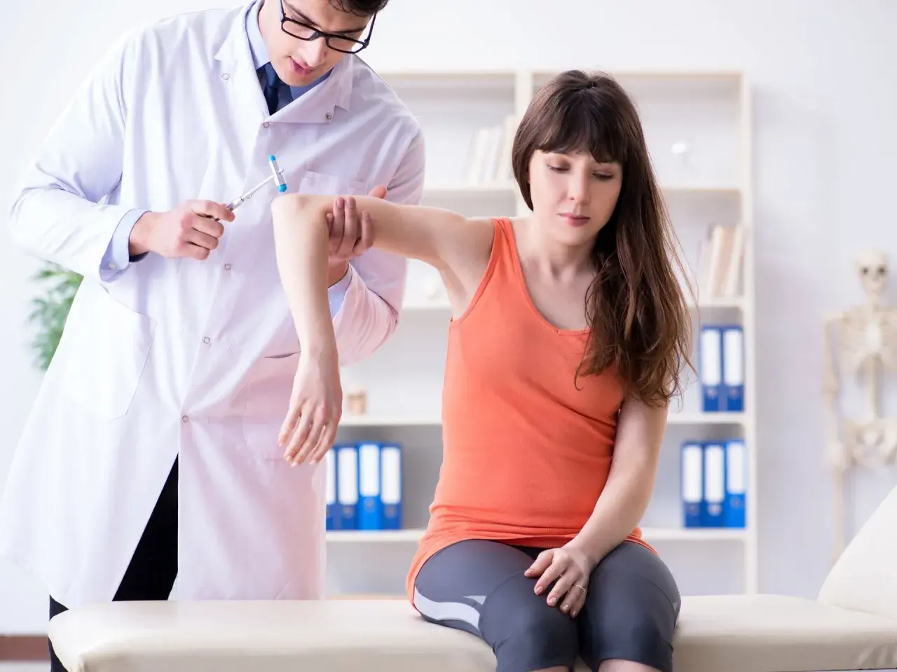 Medico esegue un esame neurologico su una paziente, testando i riflessi del braccio con un martelletto.