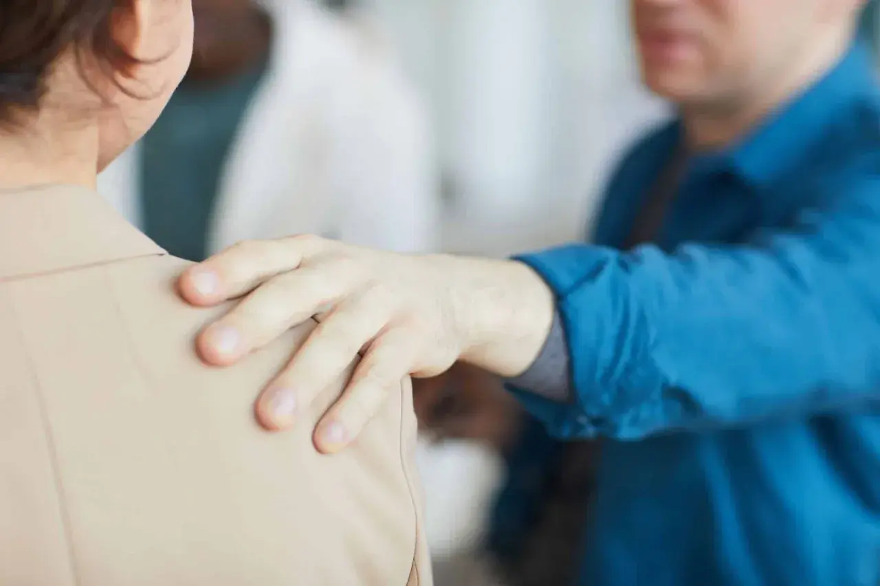 Mano appoggiata sulla spalla, un gesto di supporto. Forse un collega che fa un "jerk test" per verificare la stabilità, o un amico che offre conforto.