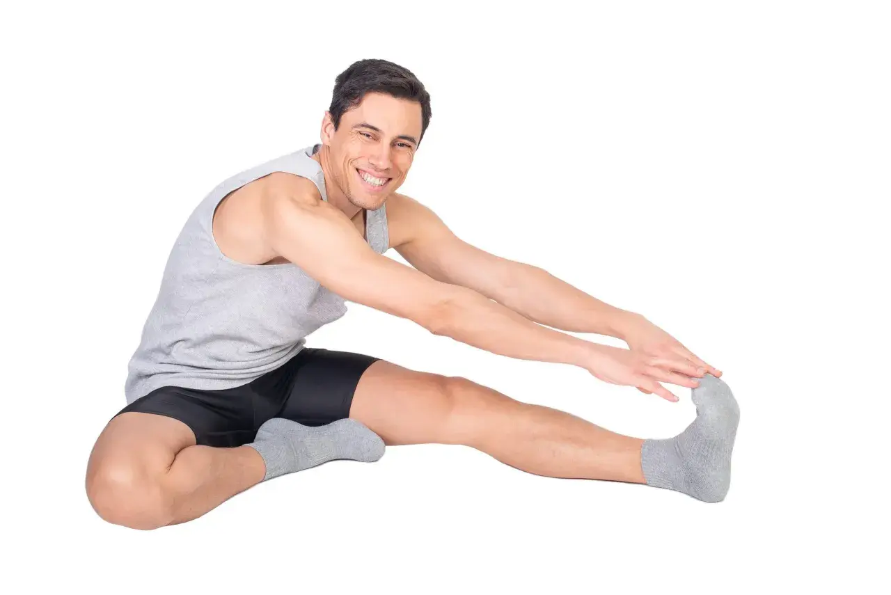 Uomo sorridente fa stretching, allungando la gamba destra. Attenzione a non forzare per evitare una lesione bicipite femorale.