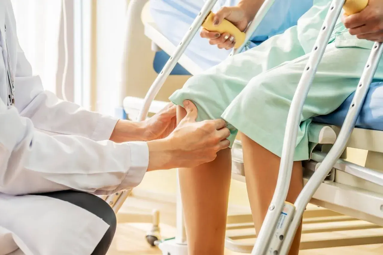 Medico esegue il Lachman test su un paziente in ospedale, valutando la stabilità del ginocchio.