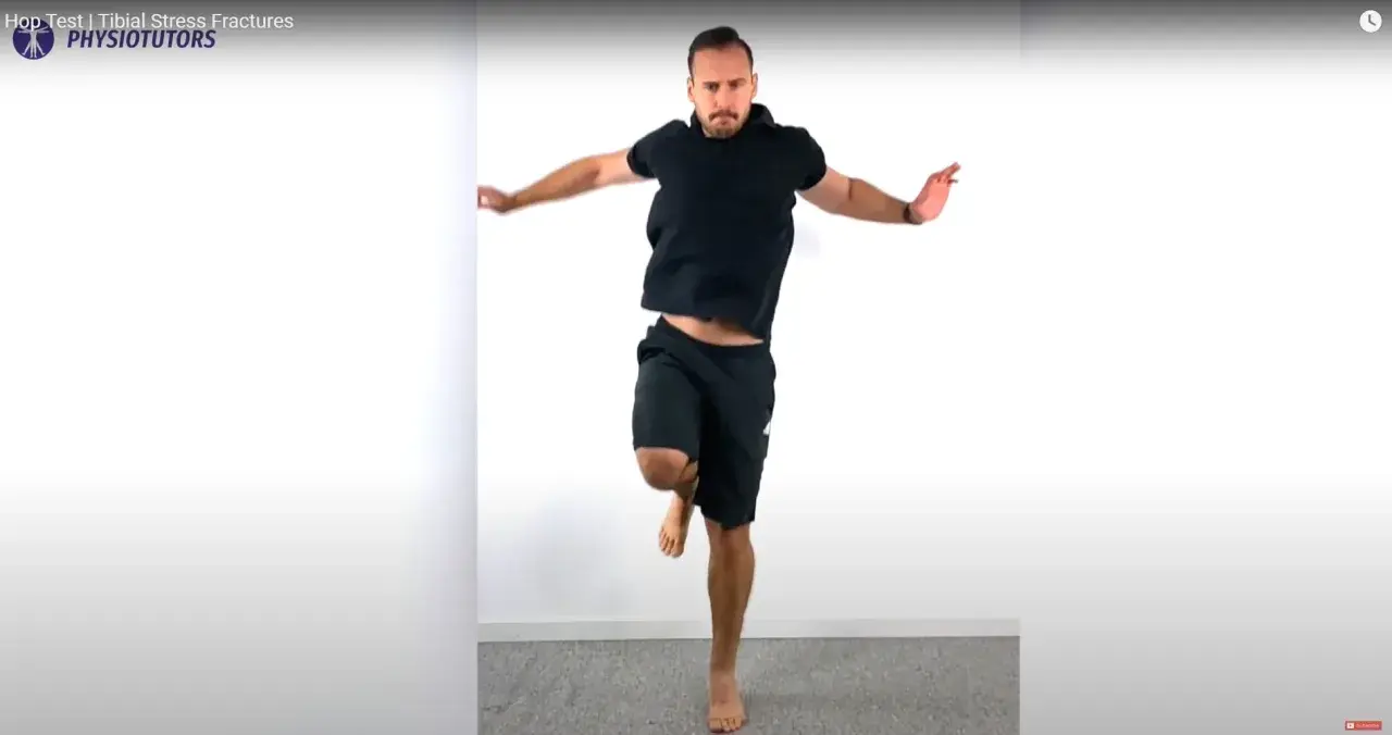 Uomo in nero esegue un hop test, saltando su una gamba sola.