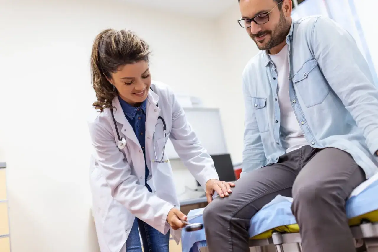 Medico esegue un esame neurologico su un paziente, testando i riflessi con un martelletto.