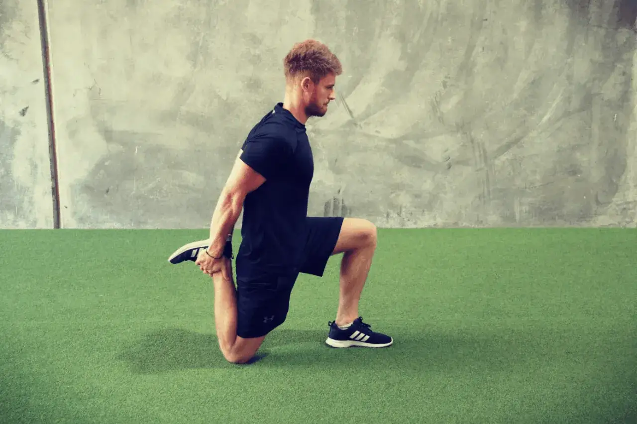 Uomo con capelli rossi esegue stretching quadricipiti per alleviare la stiffness muscolare.