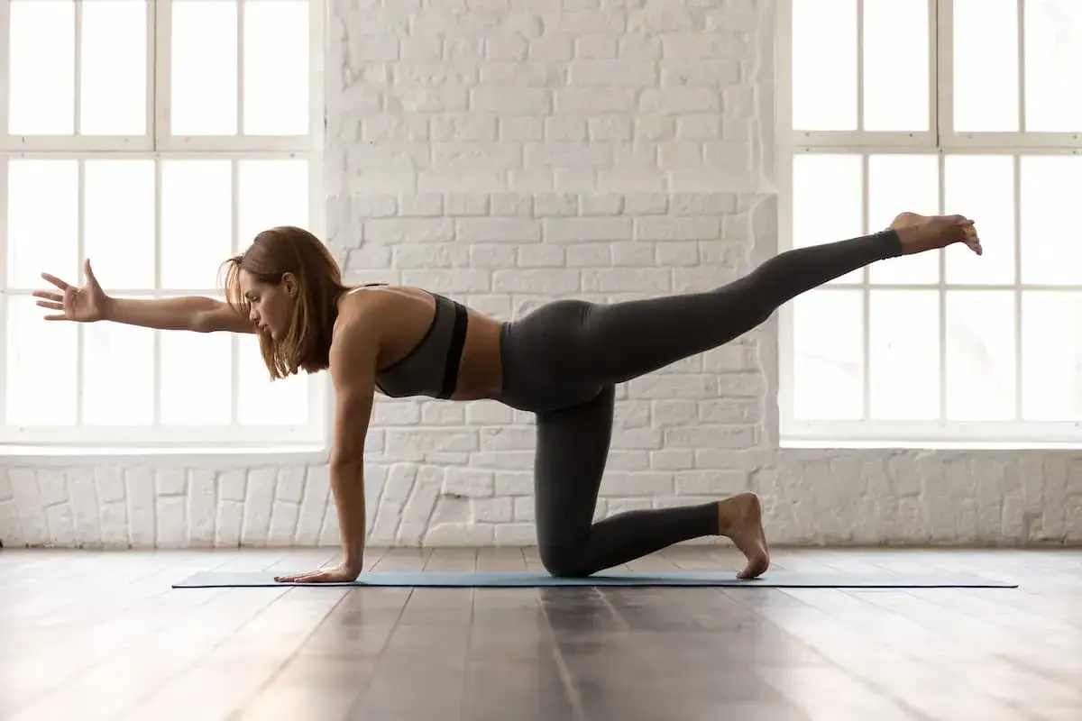 Donna in posizione yoga, con un braccio e una gamba sollevati. Attenzione agli esercizi per la diastasi addominale da evitare.